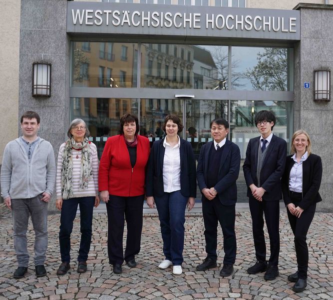 Eine Gruppe von Personen steht vor dem Eingang der Westsächsischen Hochschule Zwickau.